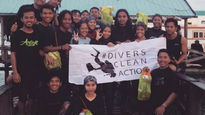 Para anggota komunitas memgang spanduk bertuliskan Divers Clean Action